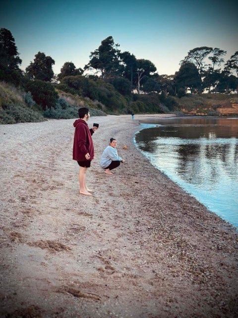 Carer with disabled boy at beach at dusk