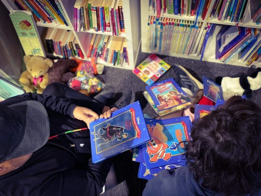 Carer with disabled boy in library looking at books together