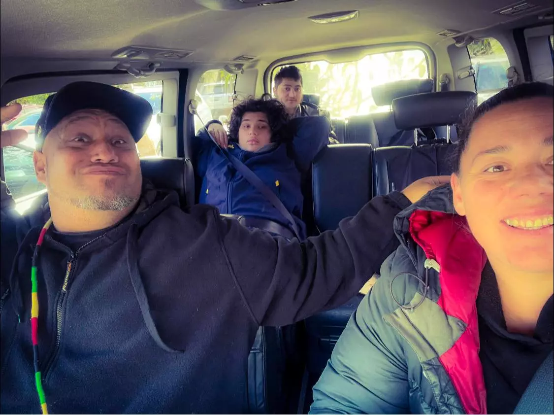 Male and female carers sitting in front seat with two disabled boys sitting in the back seat of van