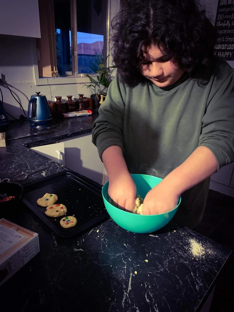 Disabled boy mixing cookie batter with his hands in kitchen at home