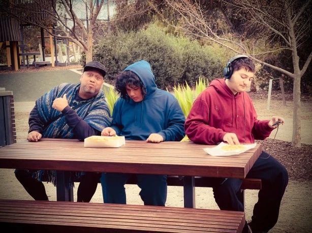 Carer with two disabled boys sitting at park picnic table